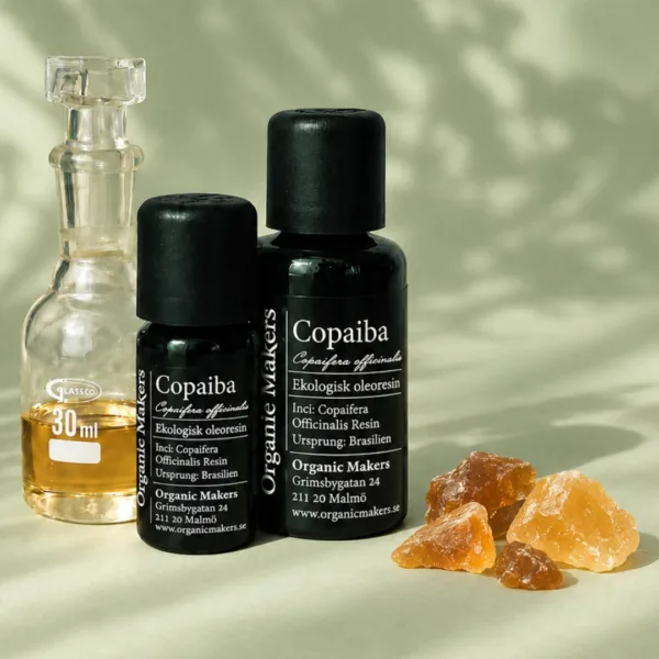 Ekologisk Copaiba oleoresin i uv-skyddande glasflaskor bredvid en glaskaraff med olja, med bitar av copaibakåda