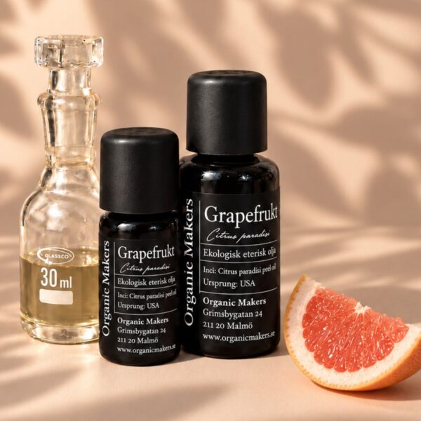 Ekologisk eterisk olja Grapefrukt i uv-skyddande glasflaskor bredvid en glaskaraff med olja, med en grapefruktklyfta