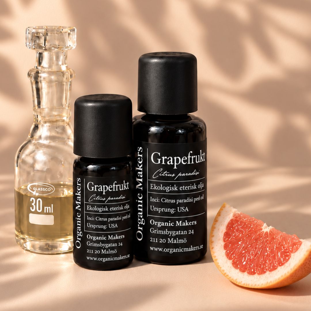 Ekologisk eterisk olja Grapefrukt i uv-skyddande glasflaskor bredvid en glaskaraff med olja, med en grapefruktklyfta
