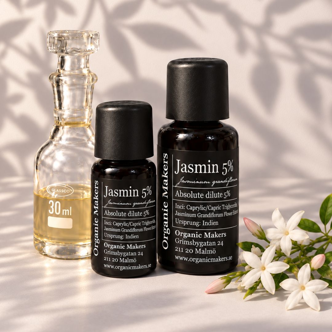 Jasmin absolut 5% i uv-skyddande glasflaskor bredvid en glaskaraff med olja, med vita jasminblommor