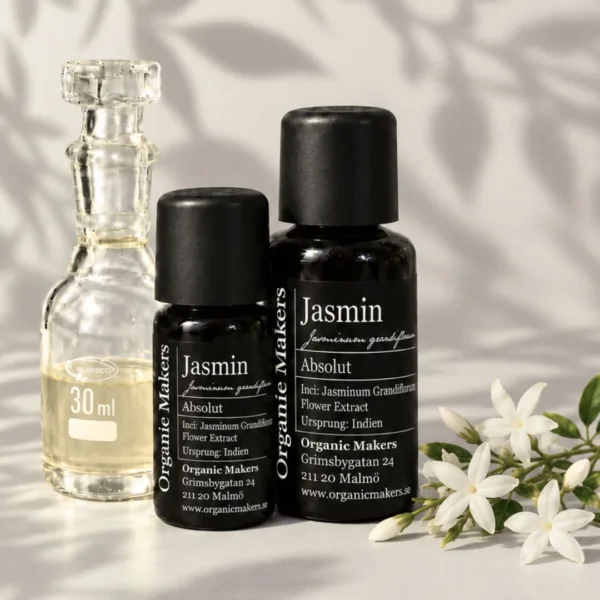 Jasmin absolut i uv-skyddande glasflaskor bredvid en glaskaraff med olja, med vita jasminblommor