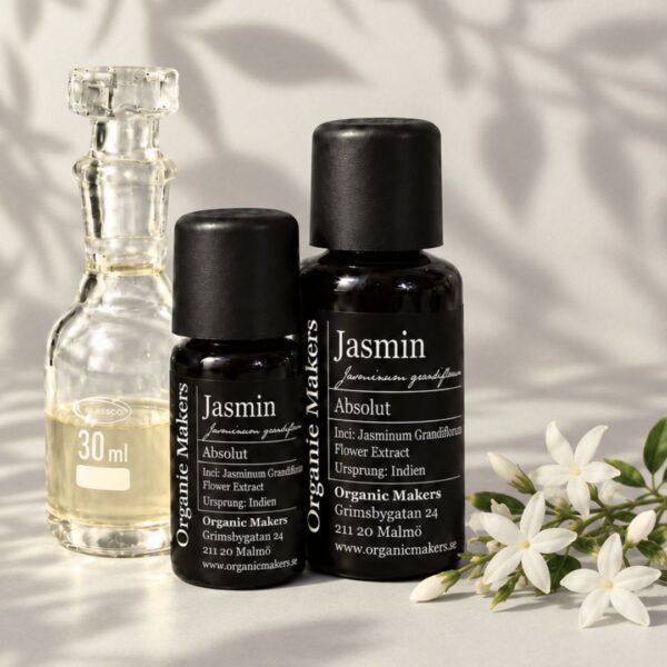 Jasmin absolut i uv-skyddande glasflaskor bredvid en glaskaraff med olja, med vita jasminblommor