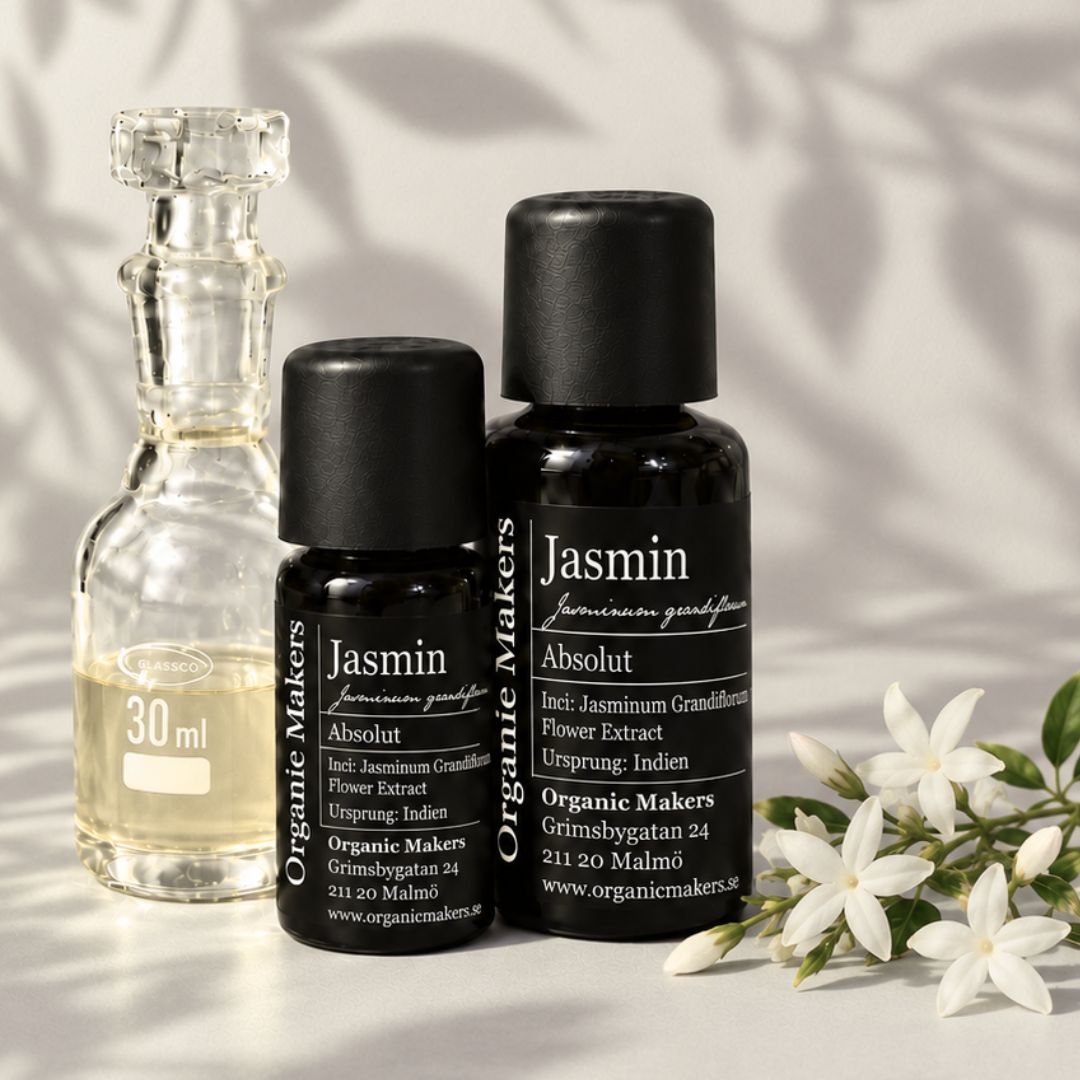 Jasmin absolut i uv-skyddande glasflaskor bredvid en glaskaraff med olja, med vita jasminblommor